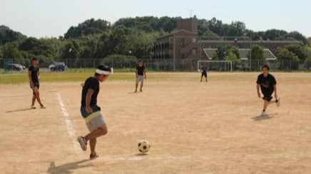 グラウンドでサッカーをする学生たち