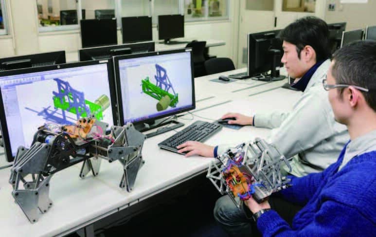 ロボットを前にパソコンで作業する在校生