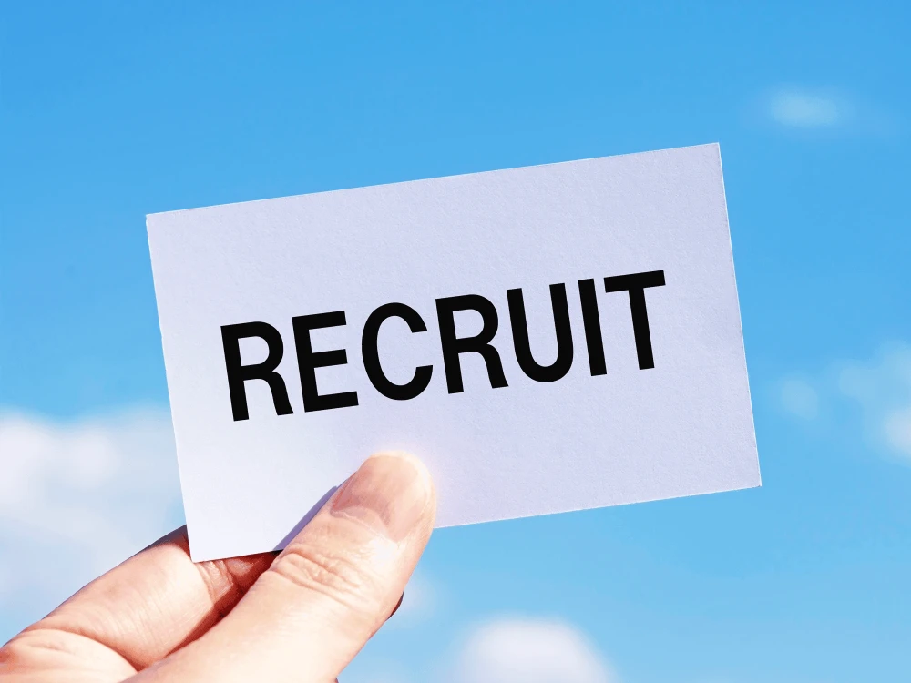「RECRUIT」と書かれたカードを持つ手（イメージ）