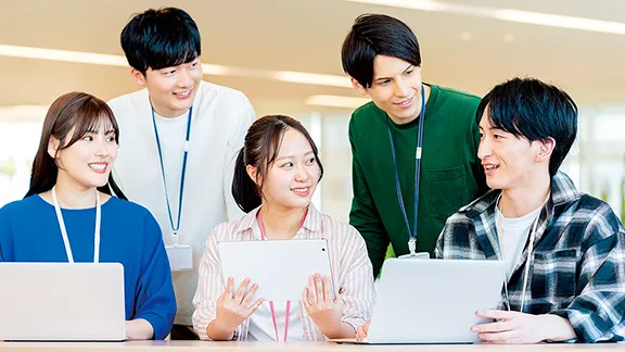 ノートパソコンを囲んで話す学生たち